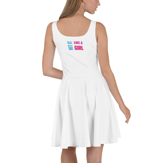 Woman wearing a white sleeveless skater dress patterned with the "Bold. Fierce. Confident." Hit It Like a Girl logo, combining sporty energy with feminine empowerment.