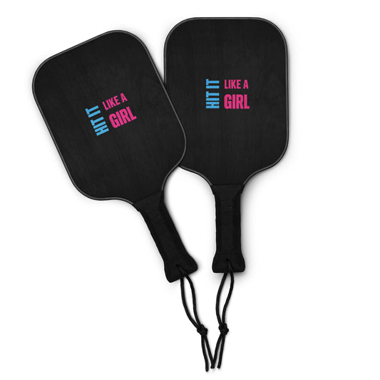 Empowering pickleball set featuring two black paddles with Hit It Like a Girl branding and bright yellow balls — perfect for fierce women on the court.