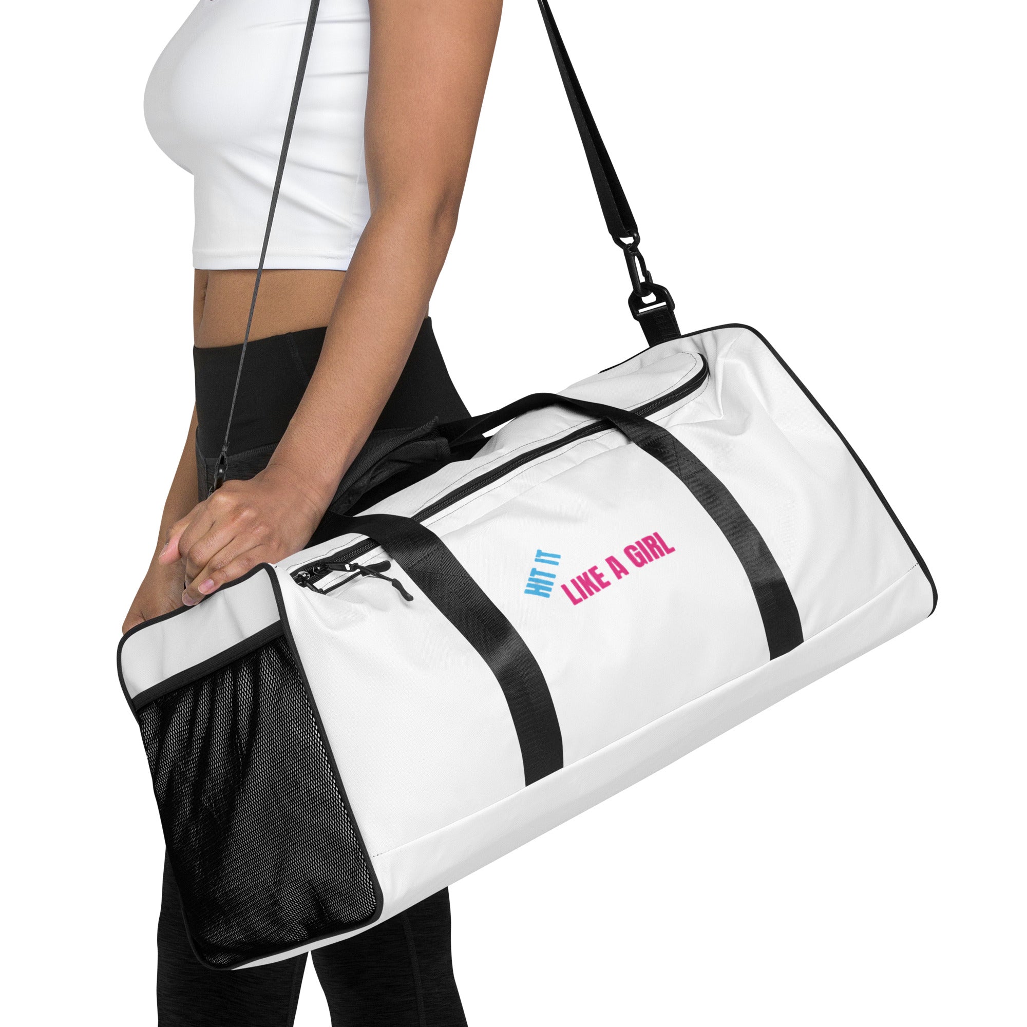 Woman carrying white Hit It Like A Girl duffel bag with black straps and bold pink and blue logo