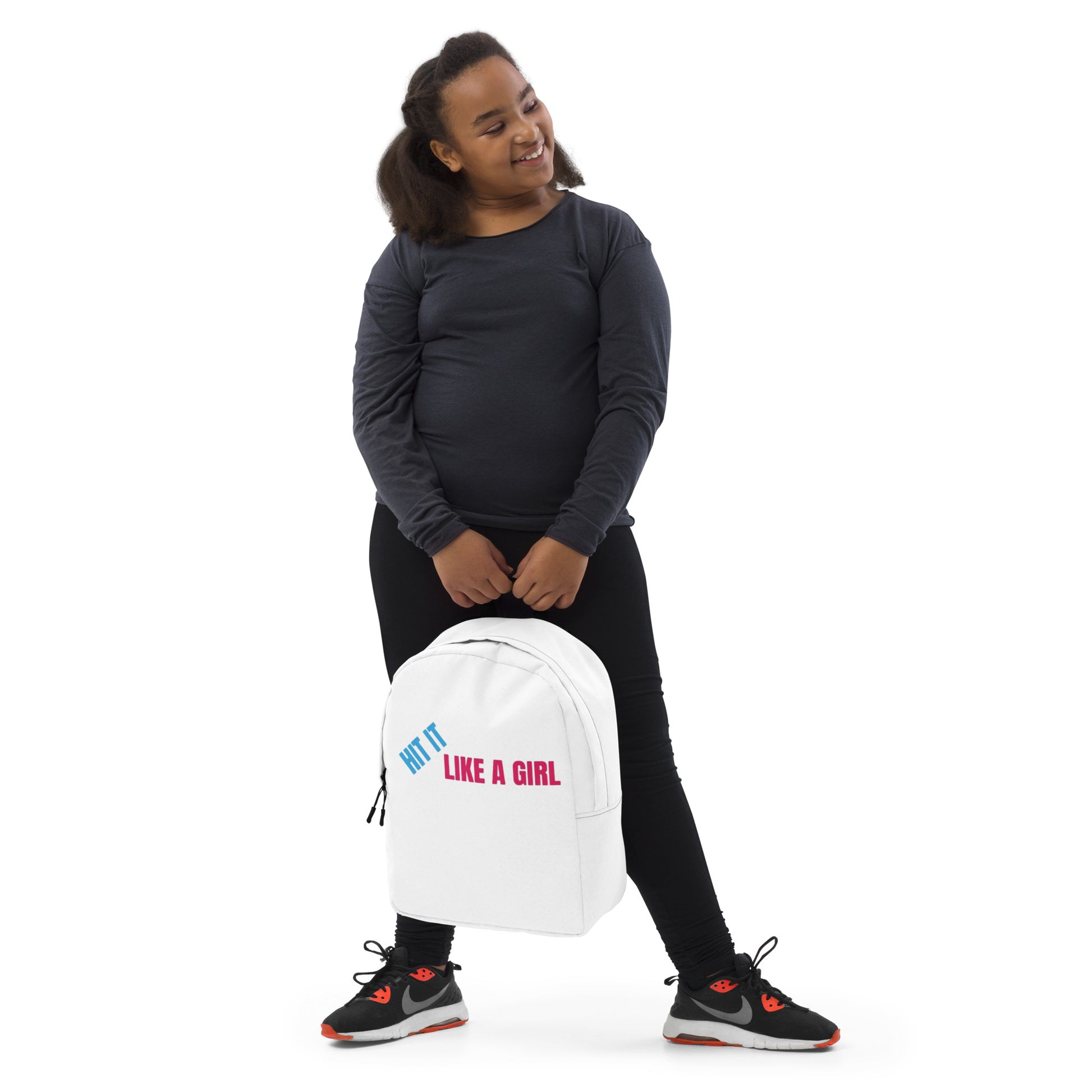 Young girl in black activewear holding a white ‘Hit It Like a Girl’ backpack—sporty, stylish gear for confident athletes on the rise.