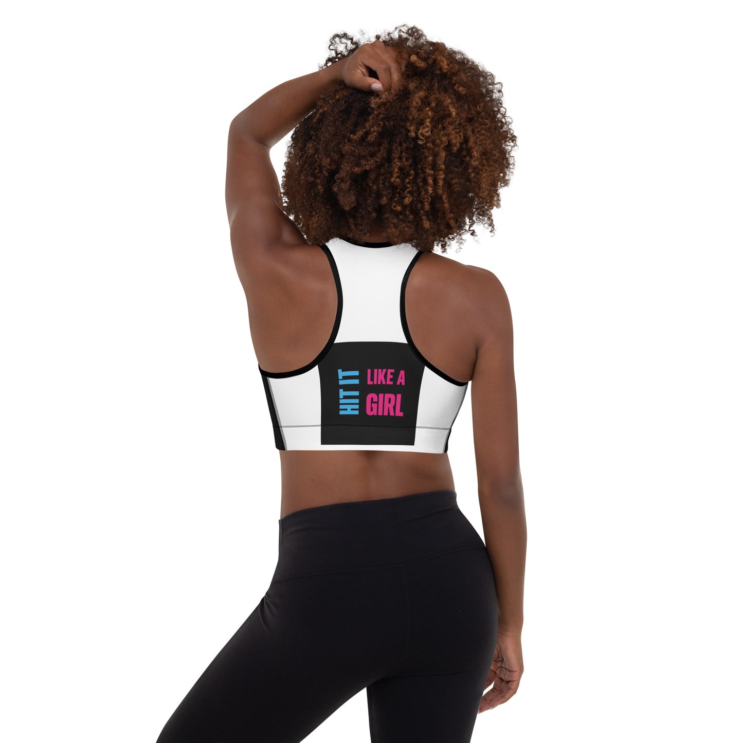 Smiling woman wearing a black "Hit It Like a Girl" sports bra with bold pink and blue text, styled for athletic wear or active lifestyle branding.