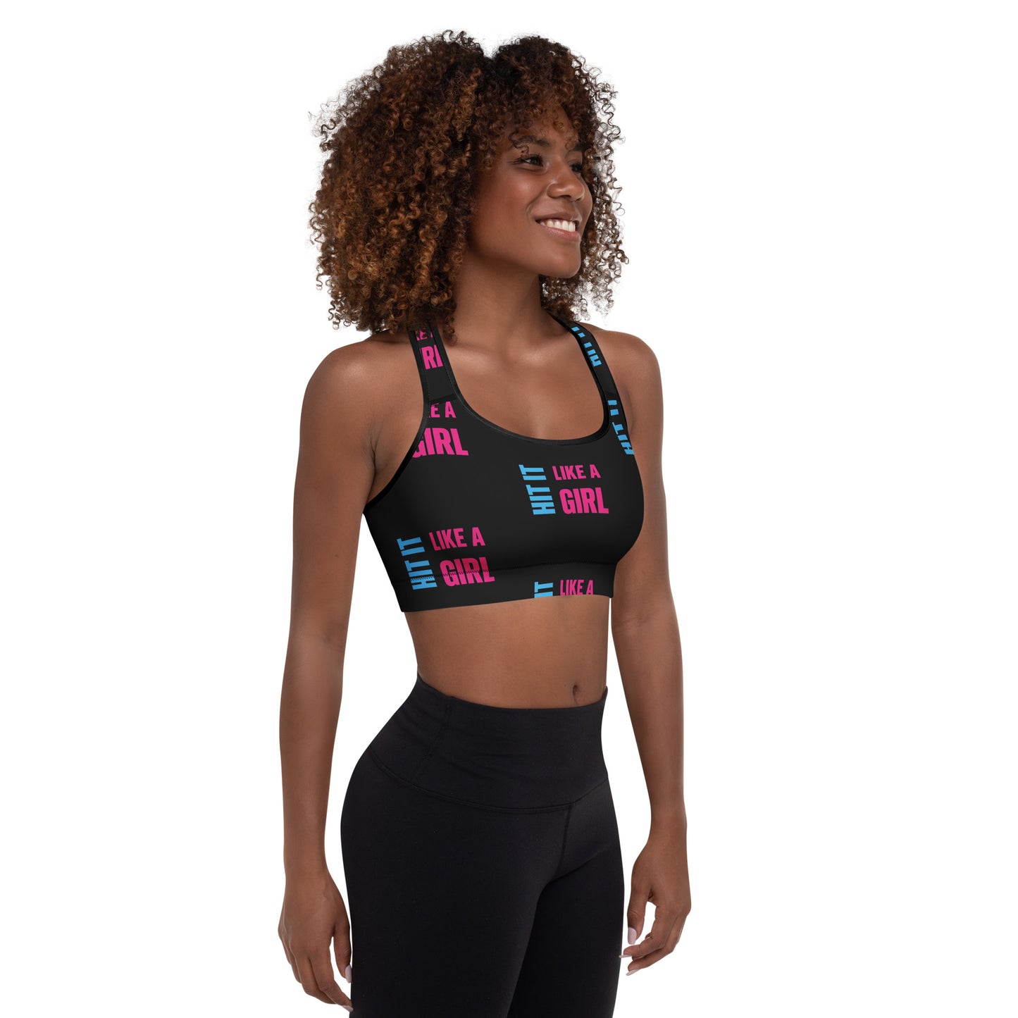 Smiling woman wearing a black "Hit It Like a Girl" sports bra with bold pink and blue text, styled for athletic wear or active lifestyle branding.