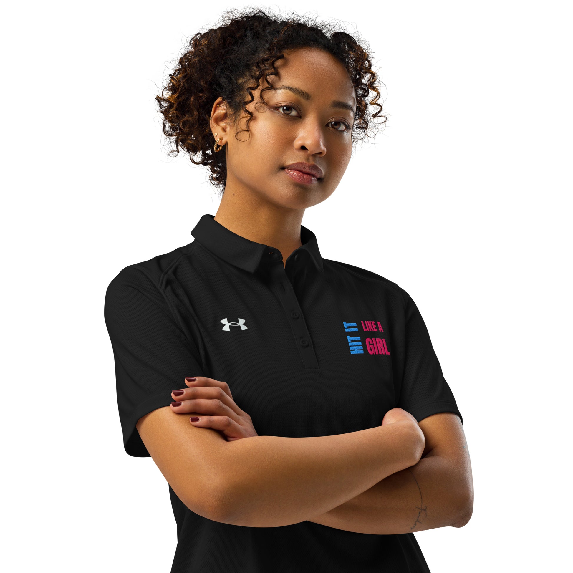 Confident woman wearing black Under Armour polo shirt with “Hit It Like a Girl” logo, showcasing athletic-inspired empowerment and sporty style.