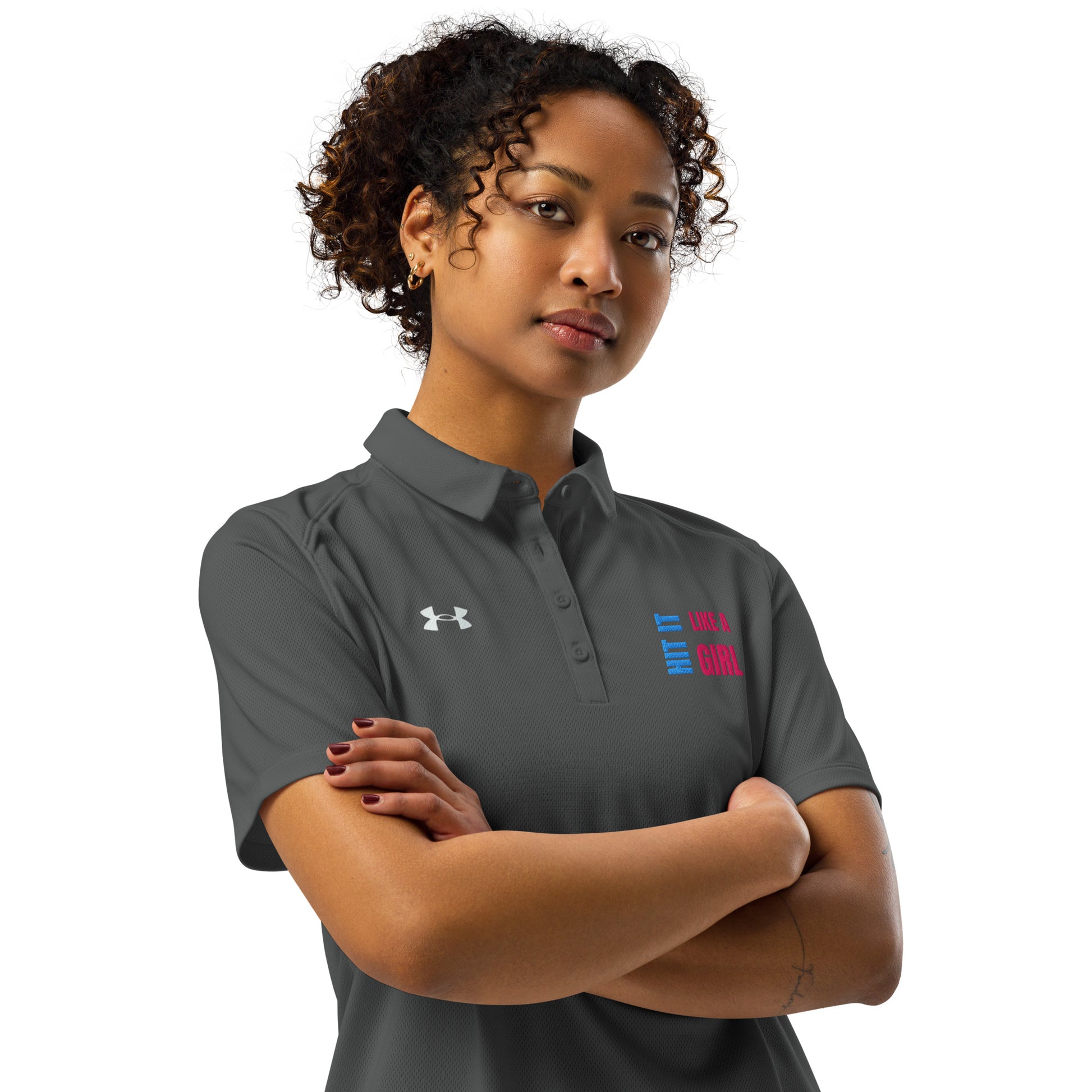 Confident woman wearing gray Under Armour polo shirt with “Hit It Like a Girl” logo, showcasing athletic-inspired empowerment and sporty style.