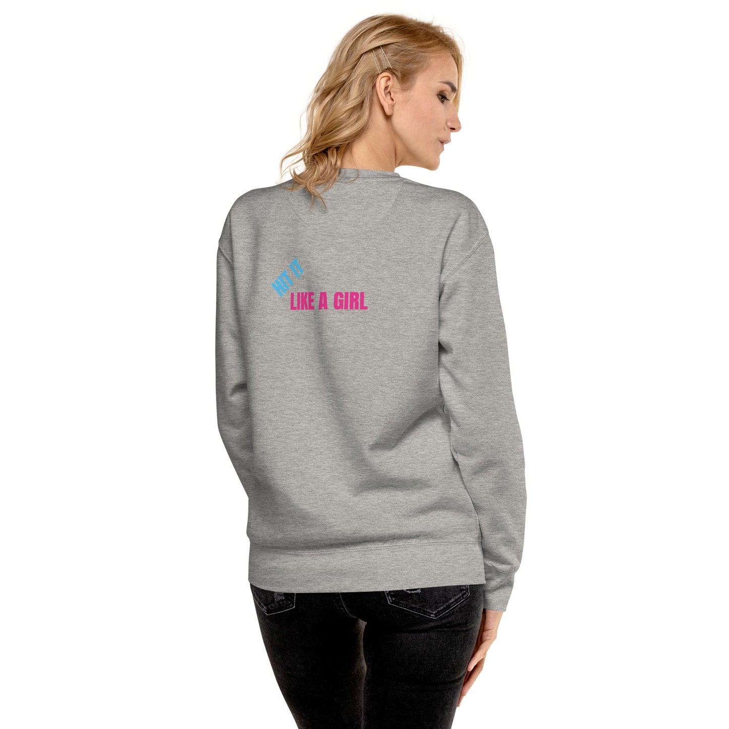 Back view of a blonde woman wearing a gray fleece sweatshirt featuring the bold "Hit It Like a Girl" logo in blue and pink, with product quality callouts including tightly knit 3-end fleece, double-needle stitched details, and premium fabric features.